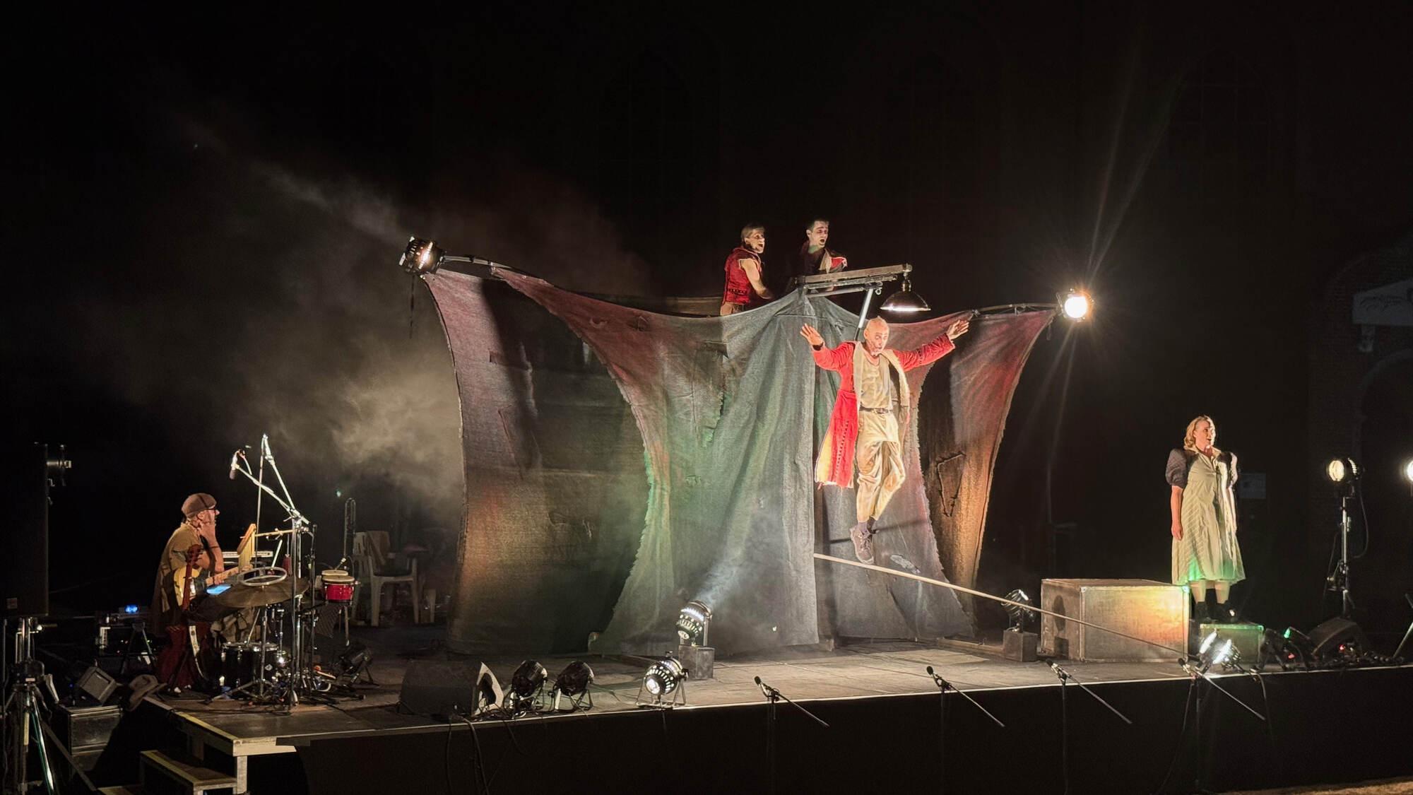 Finale von „Till Eulenspiegel“: Darsteller mit ausgebreiteten Armen im Scheinwerferlicht