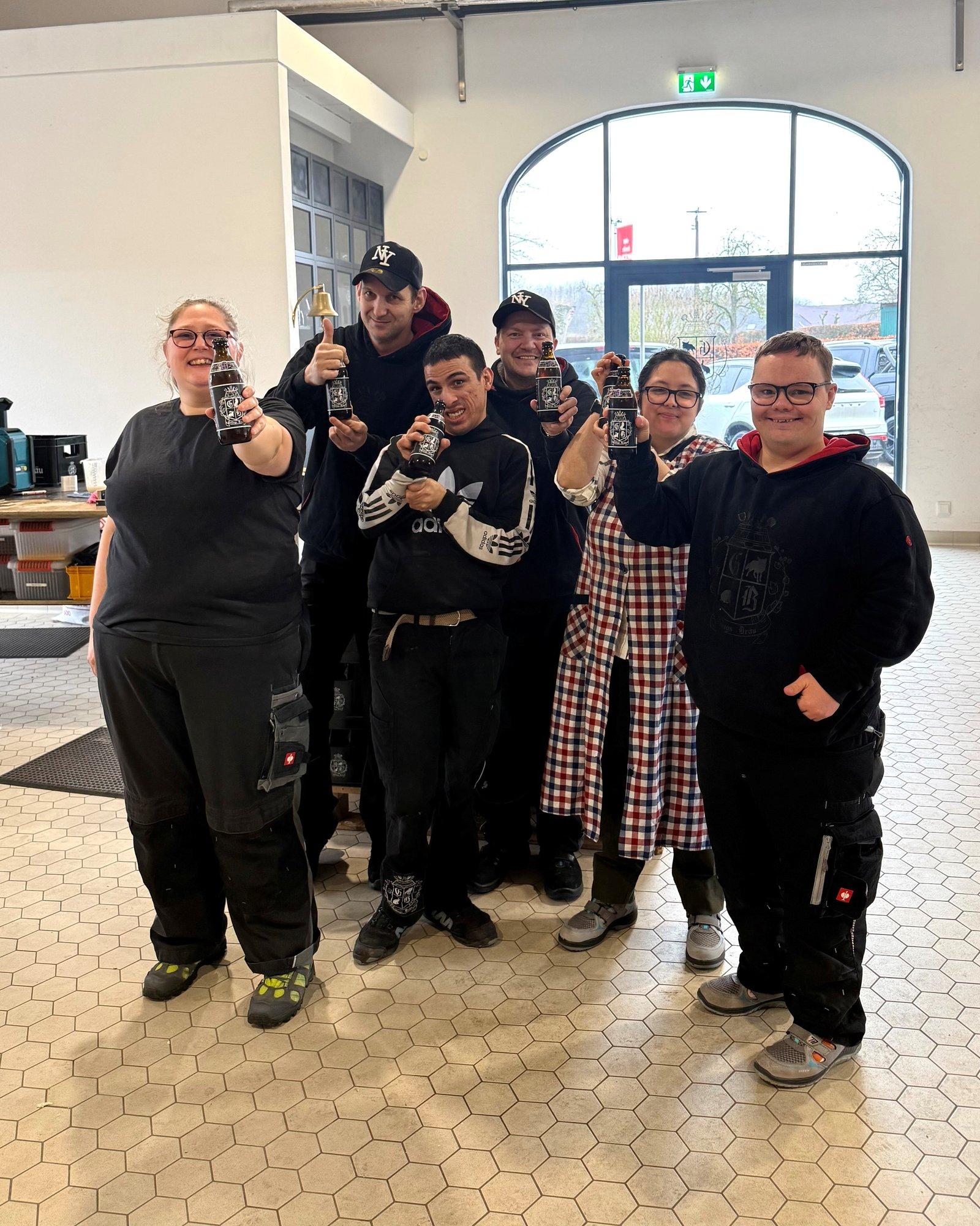 Team der Caritas-Werkstätten Niederrhein mit Flaschen von Geilings Bräu, die dort etikettiert werden