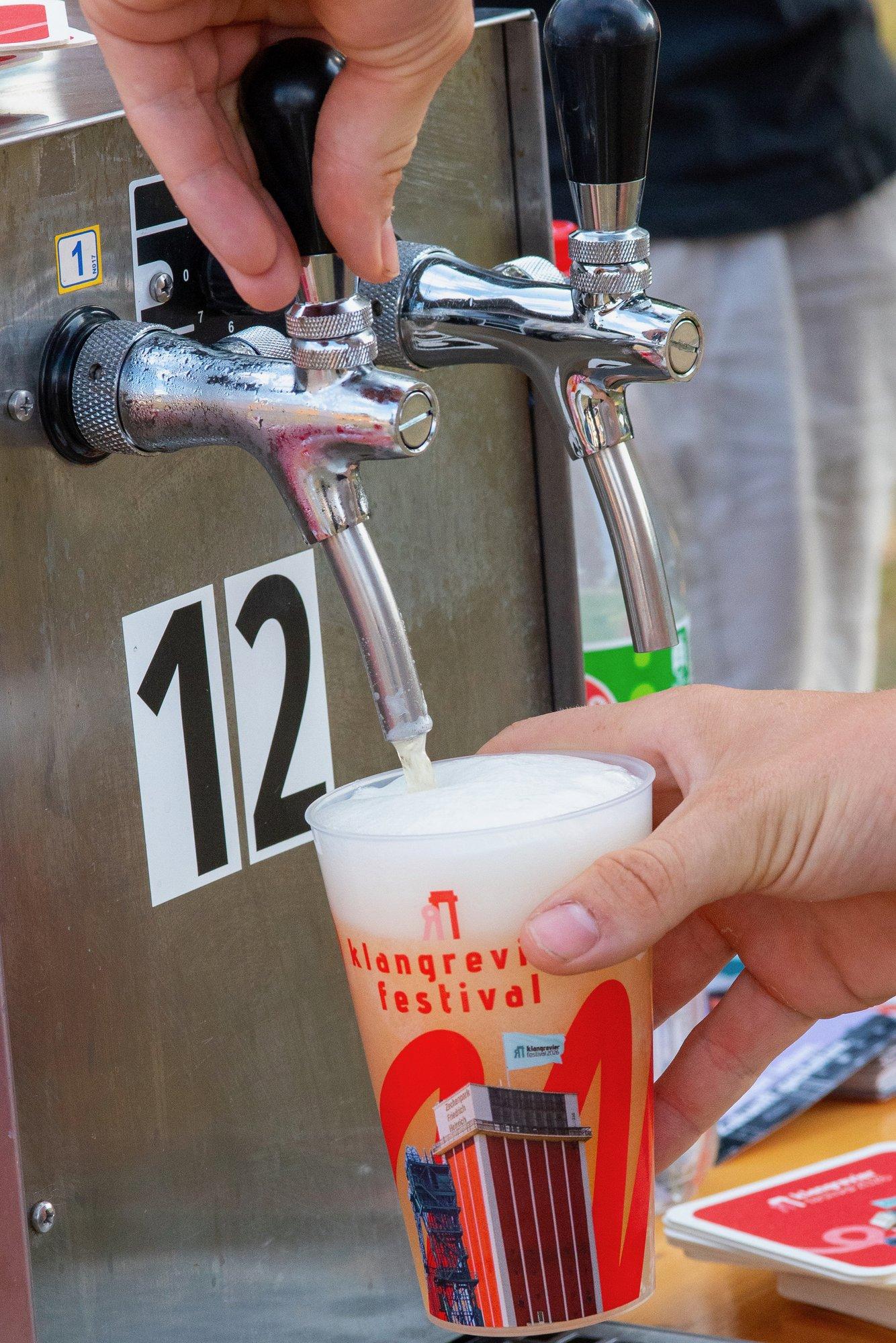 Frisch gezapftes Bier läuft in einen Becher mit klangrevier-festival-Aufdruck