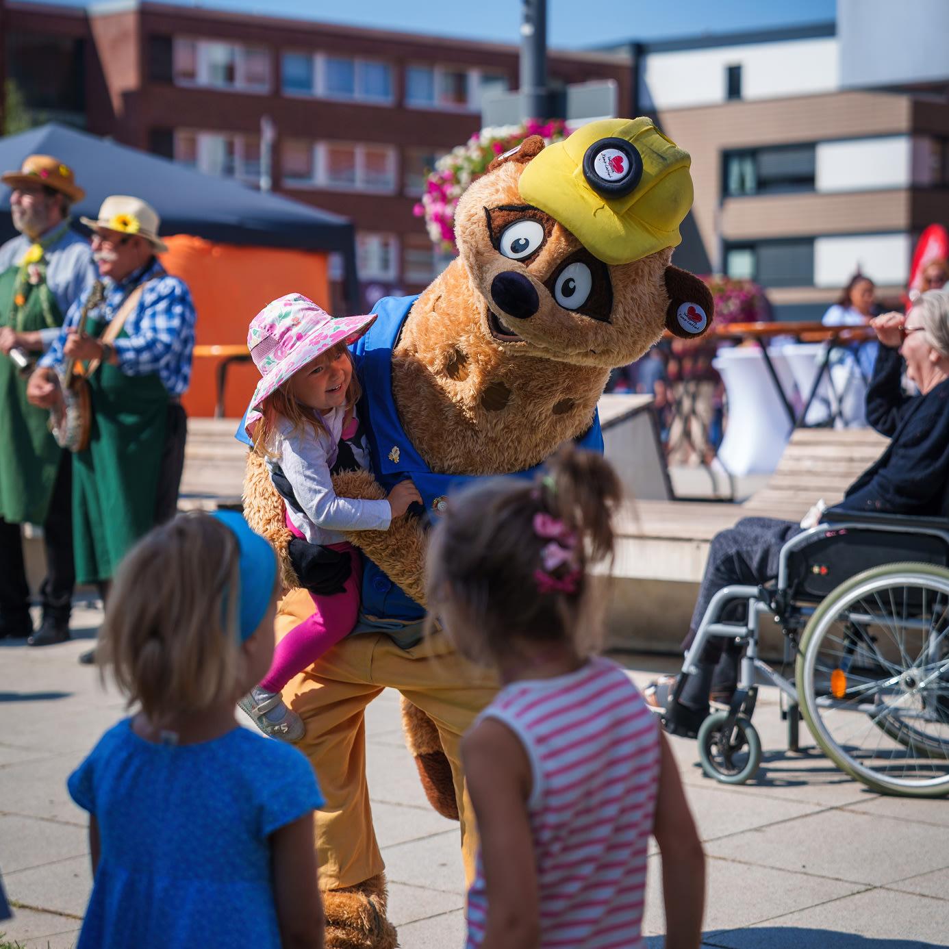 Kalli, das Maskottchen der Stadt Kamp-Lintfort, spielt mit Kindern auf dem Stadtgartenfest 2025.