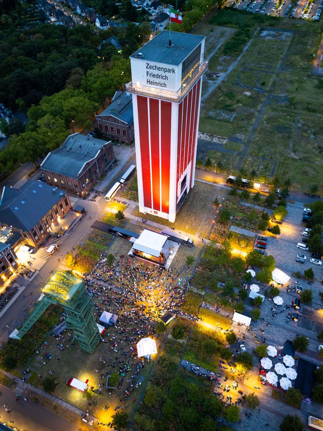Drohnenaufnahme der Big Band der Bundeswehr, die im Zechenpark vor dem Förderturm auftritt.
