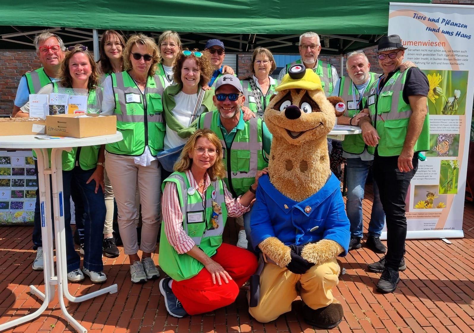Ehrenamtliche des Fördervereins Landesgartenschau Kamp-Lintfort in grünen Westen mit Maskottchen Kalli am Infostand beim Stadtgartenfest